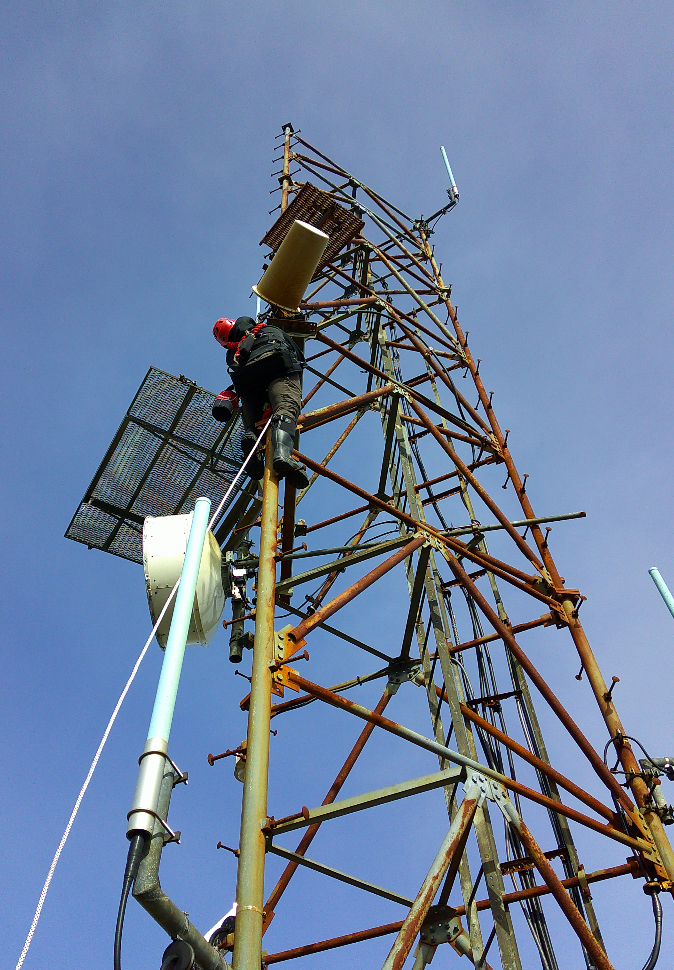 Person in climbing gear on metal tower.